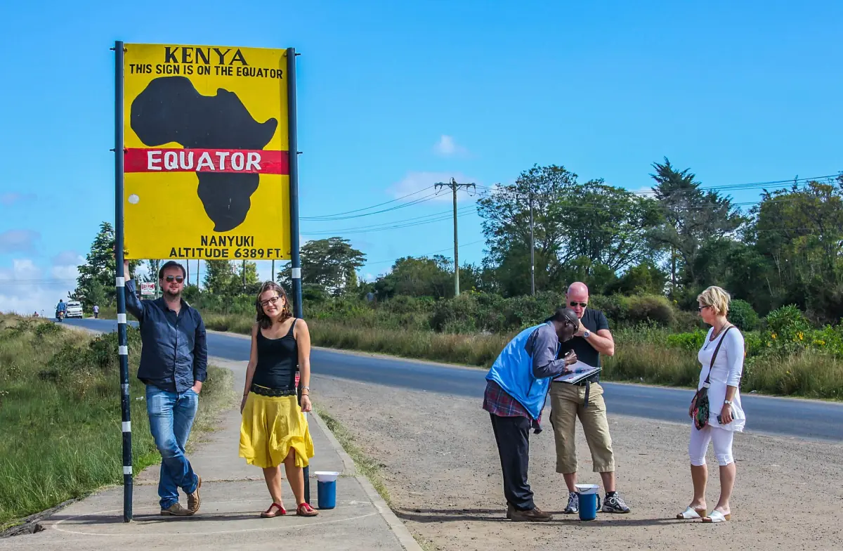 Yellow roadside equator sign shaped like Africa beside the main road