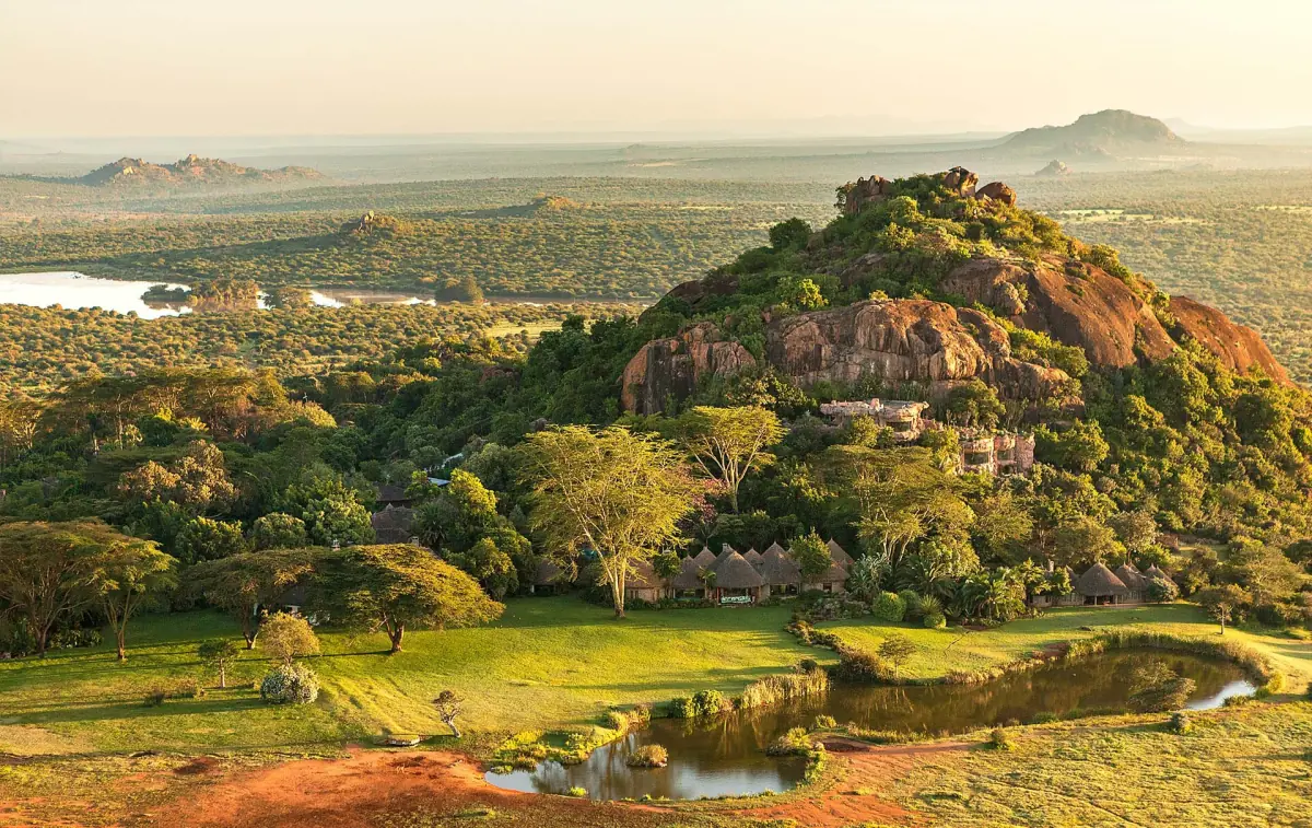 Rocky hill rising from tree-covered Laikipia plateau in warm evening light