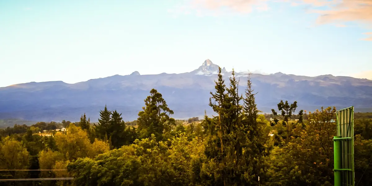 Long view of Mount Kenya peaks above forest and hills near Nanyuki