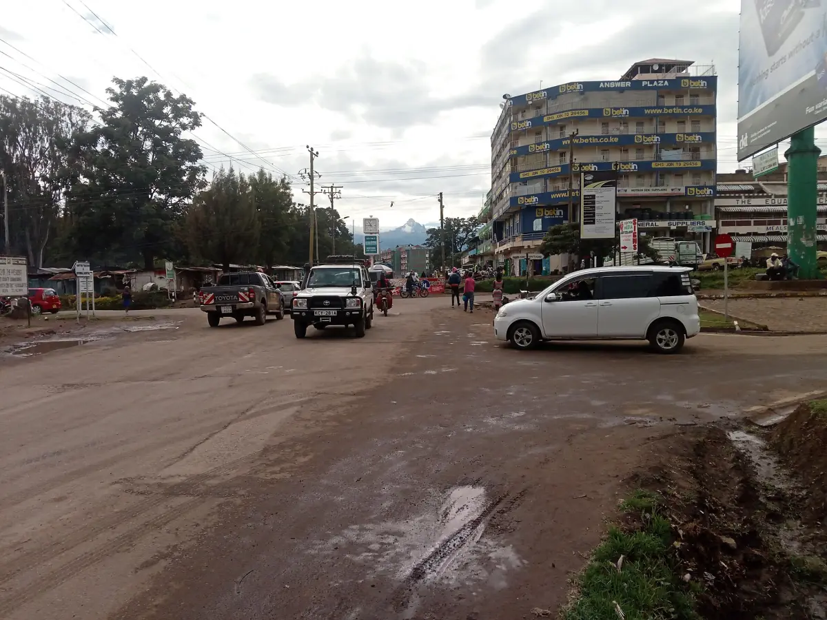 Main street of Nanyuki with buildings, parked cars and hills behind